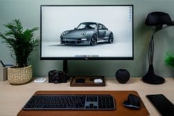 A desk with a monitor, keyboard, mouse and a car.
