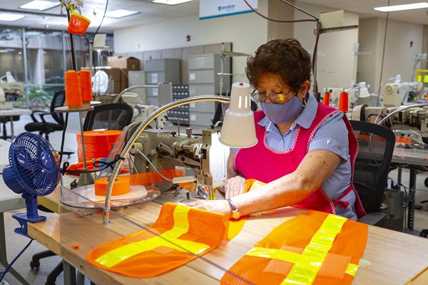 Woman working on sewing safety apparel.