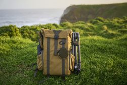 a backpack sits on a grassy field next to the ocean.