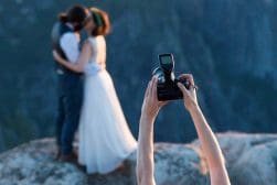 A bride and groom taking a picture with a camera.