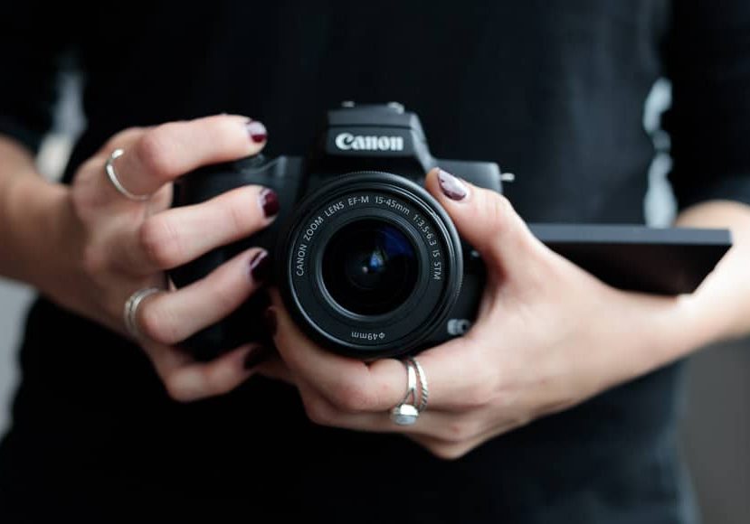 A woman holding a canon eos camera.