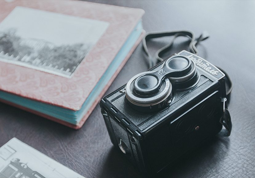 an old camera on a table next to a photo album.