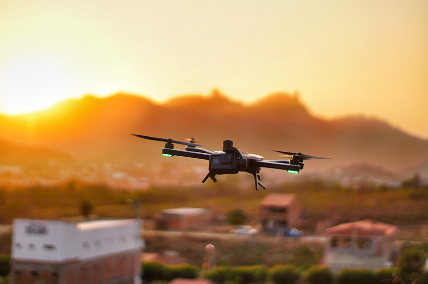 a drone with a go pro camera flying over a city at sunset.