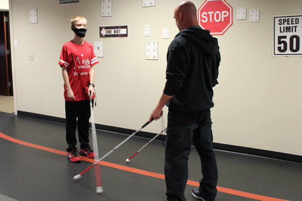 Ray Oddis and Caleb Tobias practicing Caleb's white cane in Envision's Independence Boulevard