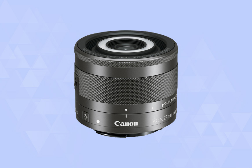 a Canon EF-M 28mm f/3.5 Macro IS STM camera lens on a blue background.