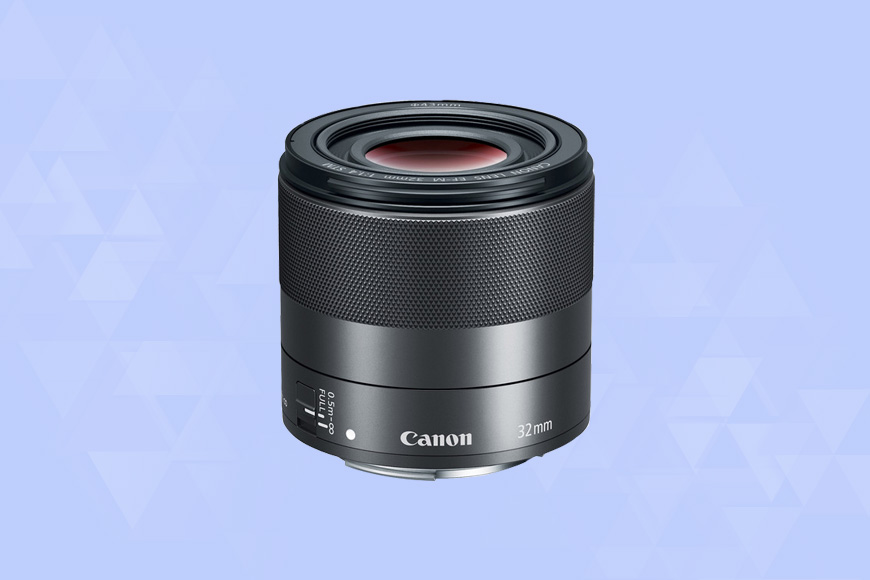 a Canon EF-M 32mm f/1.4 STM camera lens on a blue background.