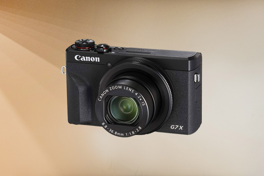 A Canon PowerShot G7X Mark III on a brown back ground