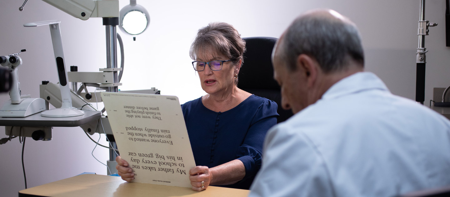 Woman in a blue shirt reads an eye test card for the doctor at the Family Vision Rehabilitation Center in Dallas.