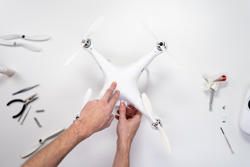 a man is repairing a white drone on a white table.