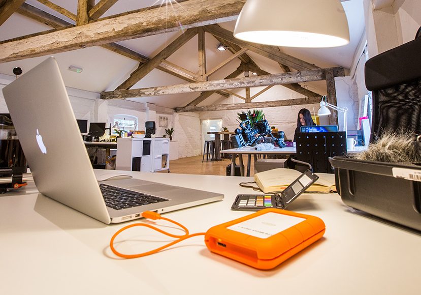 a laptop computer sitting on top of a white table next to orange external drive