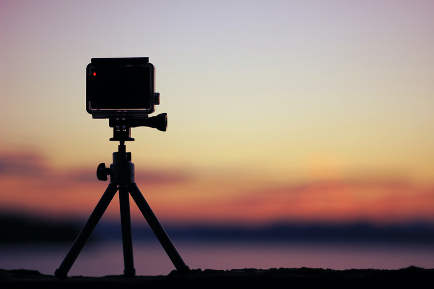 a go pro camera on a tripod with a sunset in the background.