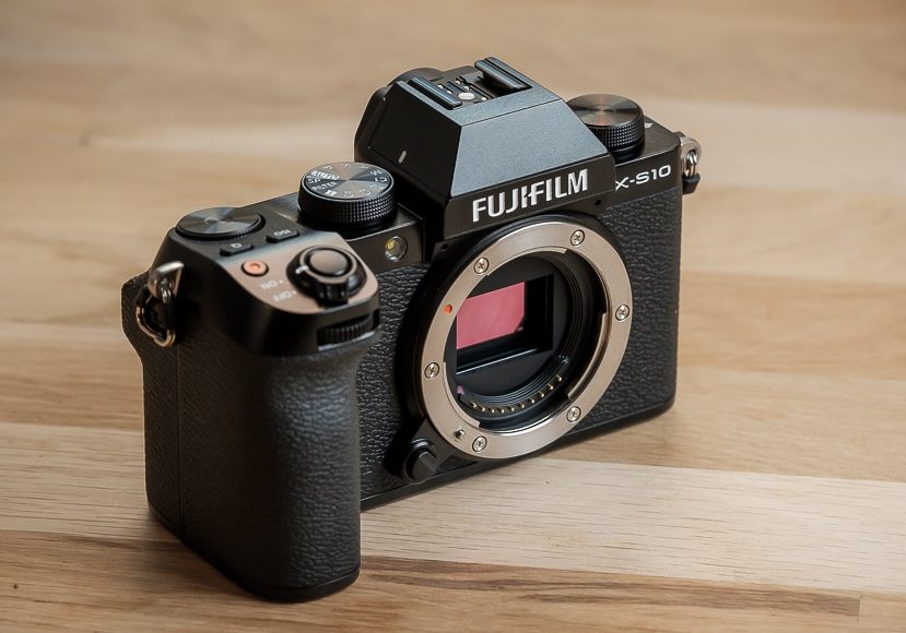 A Fujifilm X-S10 camera on a wooden table.