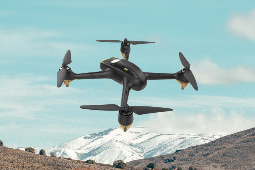 A drone flying in the sky with mountains in the background.