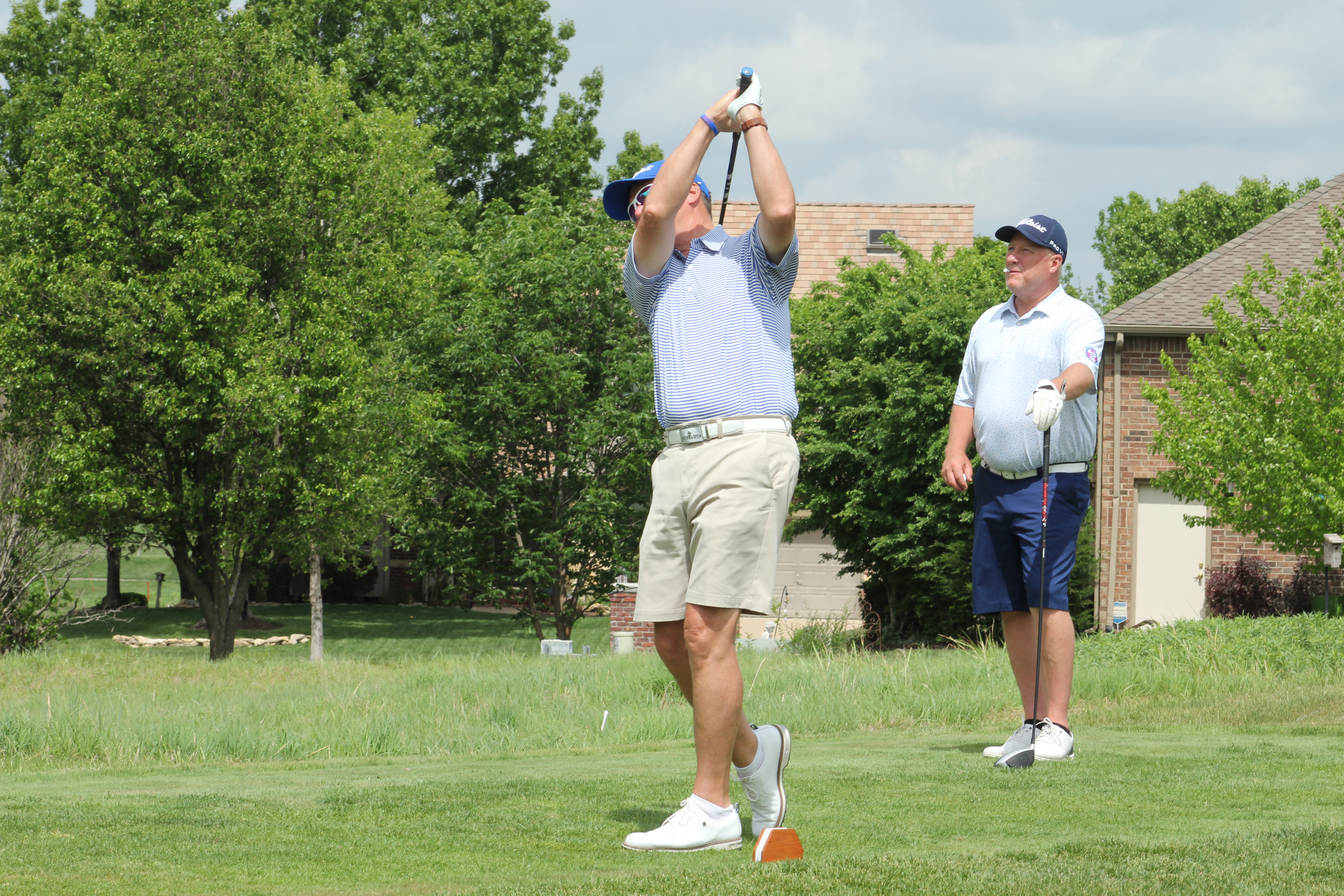 Golfer swings at ball with Terradyne Country Club in background