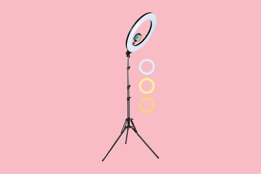 A ring light on a tripod on a pink background.