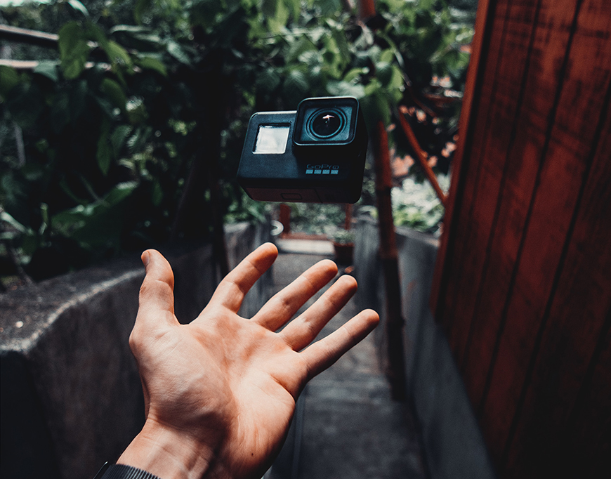 A person's hand is holding a gopro camera.