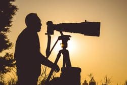 A silhouette of a man holding a camera at sunset.