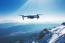 A drone flying over a snow covered mountain.