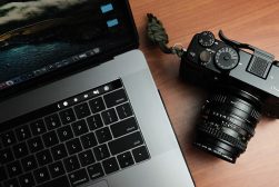 A camera next to a macbook pro laptop on a table.