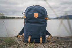 a blue backpack sitting on the shore of a lake.