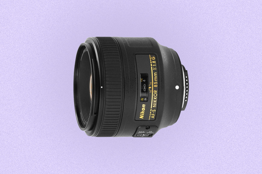 a close up of a Nikon camera lens on a purple background.