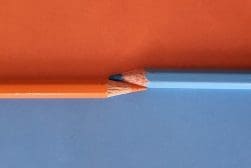 Two blue and orange pencils on a blue and orange background.