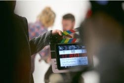 A person holding a clapper board in front of a camera.