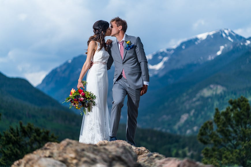 wedding couple kiss in front of mountains