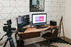 A home office with a desk, monitors, and a camera.