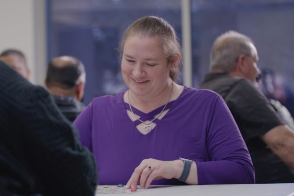 Jenny sitting at a table at Envision Dallas bingo night and smiling.