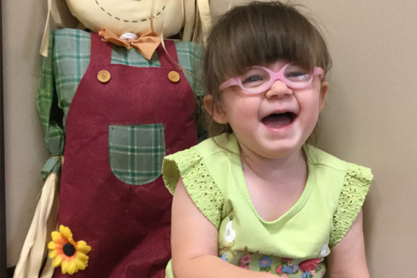 Young girl wearing pink glasses and smiling