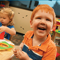 Little boy with red hair who is visually impaired enjoys playing at the new Early Childhood Development Center.