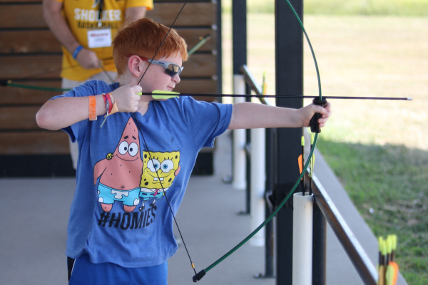 A camper shooting a bow and arrow.
