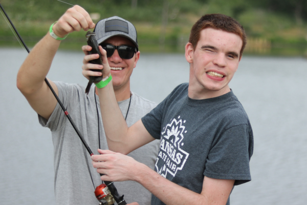 A young boy smiling as he catches a fish